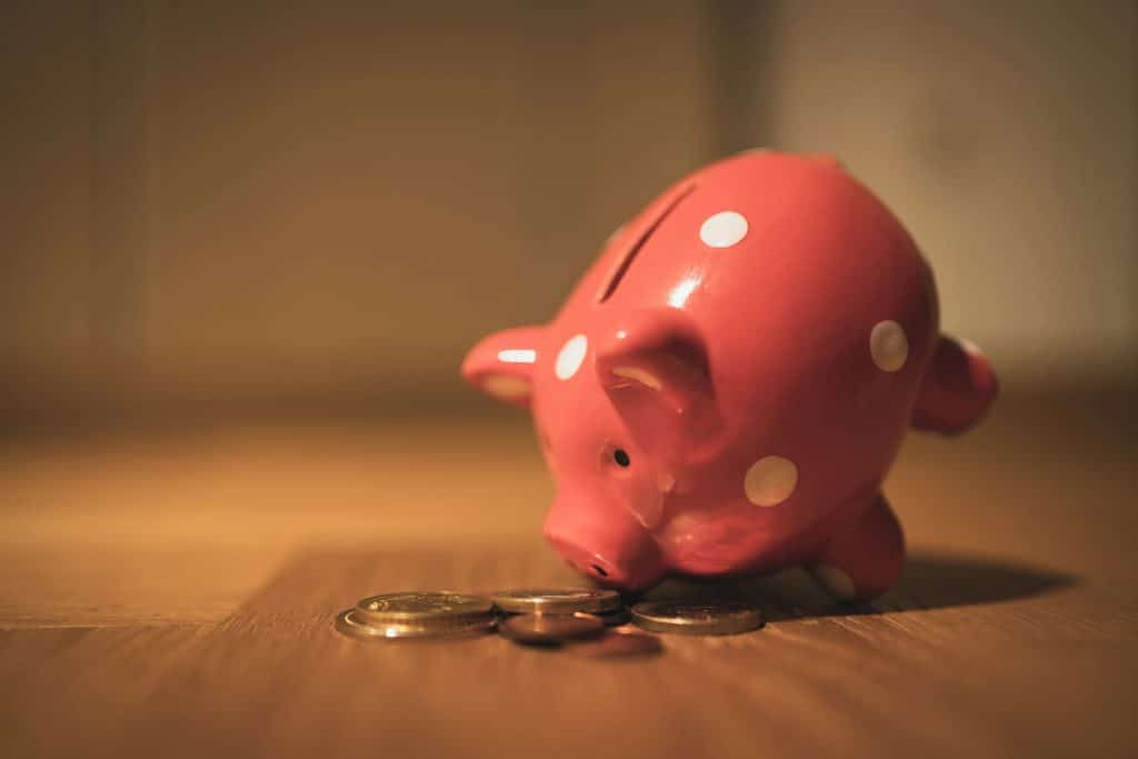 A piggy bank with coins scattered around it