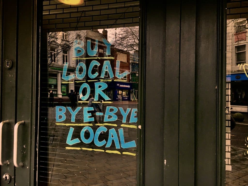 A door painted with the message Buy local or bye bye local